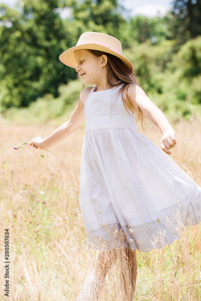 Obraz premium Little girl in a hat runs on a golden meadow