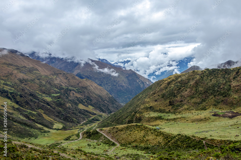 Green valley surrounded by mountains in clouds, Choquequirao trek between Yanama and Totora, Peru