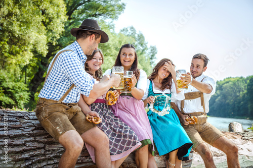 Five friends, men and women, having fun on Bavarian RIver and clinking glasses with beer