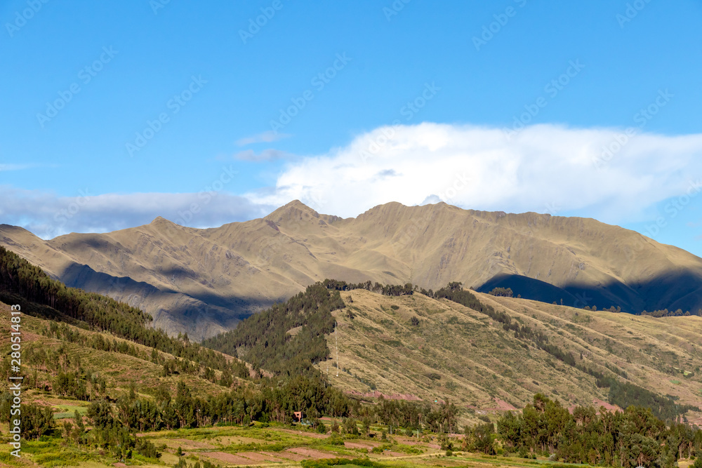 Fototapeta premium Mountain landscape with fertile valley below steep forests and ancient agricultural terraces at sunset