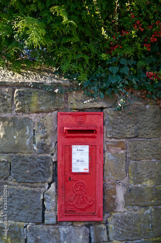 British post box in a stone wall near red holly berries British post box in a stone wall near red holly berries
