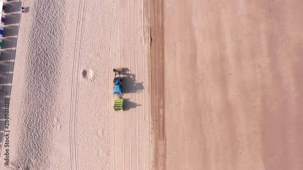 Aerial Flyover of a Tractor & Trailer Cleaning a Sandy Beach in North Devon with Beach Huts Aerial Flyover of a Tractor & Trailer Cleaning a Sandy Beach in North Devon with Beach Huts