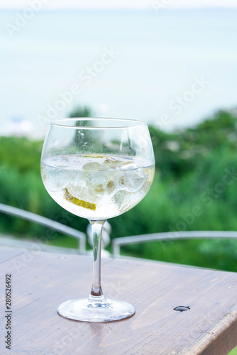 a drink served in a bar, gin and tonic, appears in a dirty wineglass