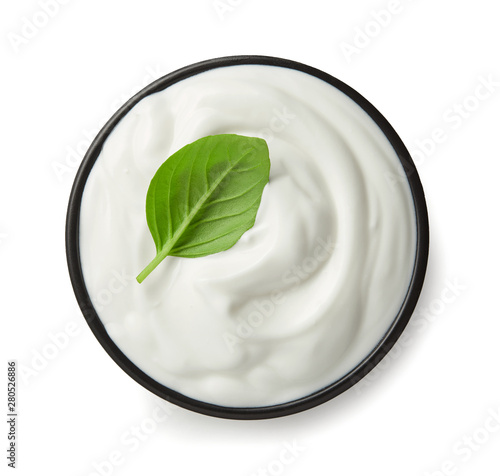 Sour cream or yoghurt is black bowl top view isolated on white background