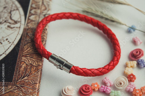  red bracelet on hand. leather bracelet on a colored background, red thread