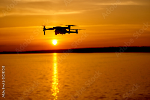 drone quadcopter with digital camera flying at sunset. Beautiful sunset on the river