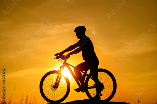 Silhouette of the cyclist riding on a sports bike at sunset. Active Lifestyle Concept. © Vadim