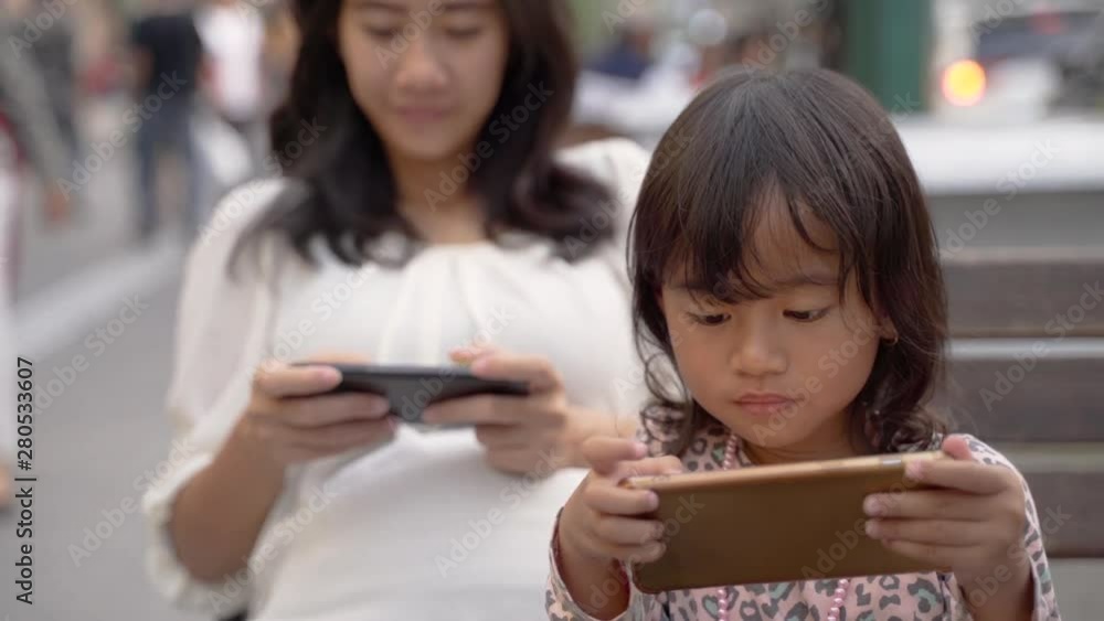 mother and her daughter playing games using smartphones