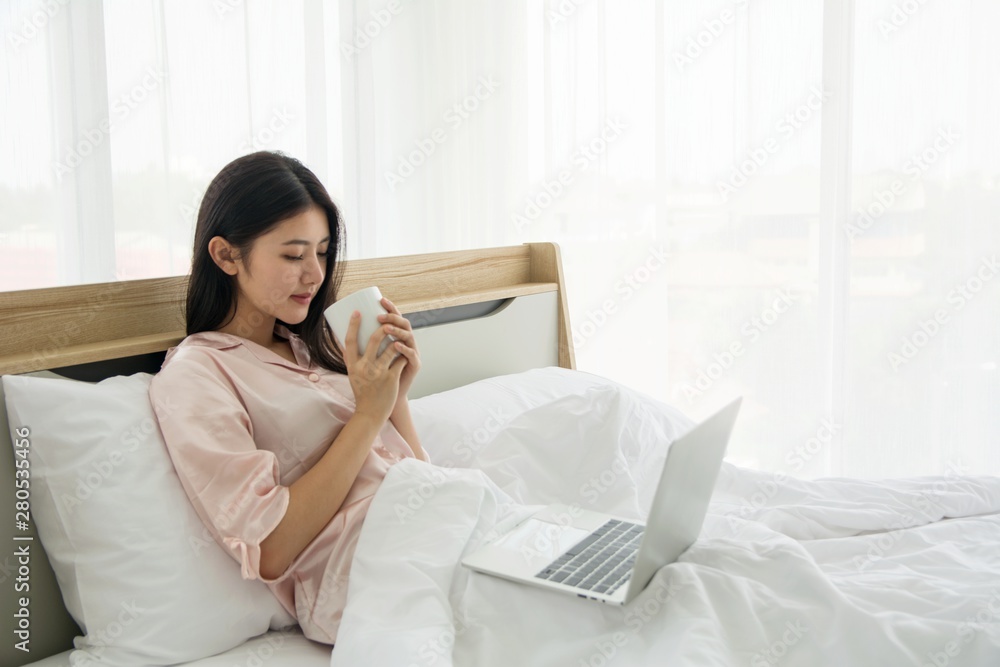 Portrait of smiling beautiful lady wake up drinking coffee working with notebook on the bed Portrait of smiling beautiful lady wake up drinking coffee working with notebook on the bed
