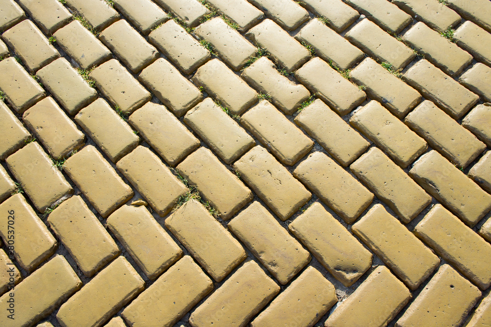 Yellow brick road sprouted by green grass under the bright summer sun Yellow brick road sprouted by green grass under the bright summer sun