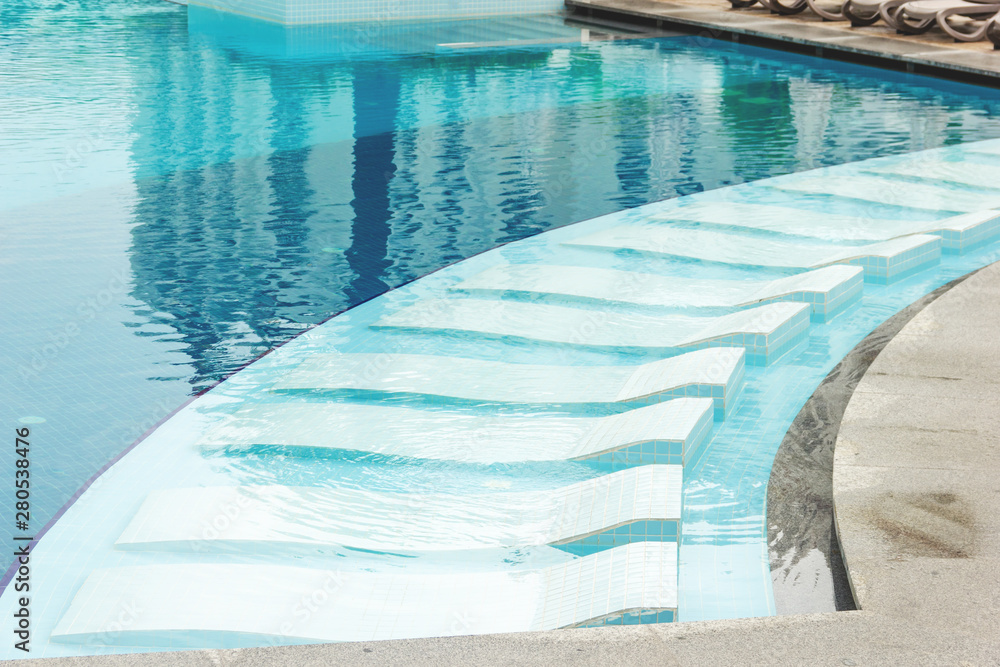 Empty places to lie in the pool on a summer day. Vacant sunbeds.