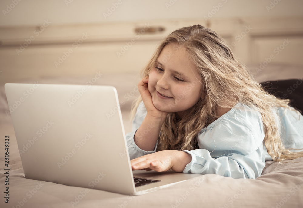 Beautiful cute little blonde girl playing and surfing the internet on laptop at home. Beautiful cute little blonde girl playing and surfing the internet on laptop at home.
