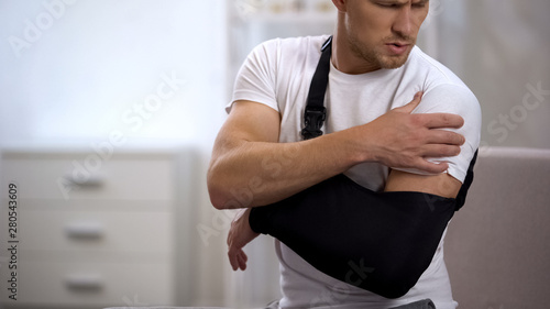 Man wearing arm sling feeling pain in shoulder, result of trauma, orthopedics photo