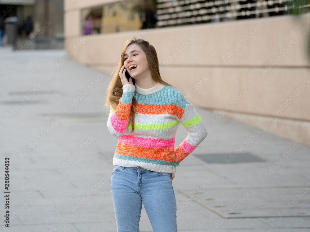 Attractive young teenager woman talking and chatting on her smart phone outside in an European city