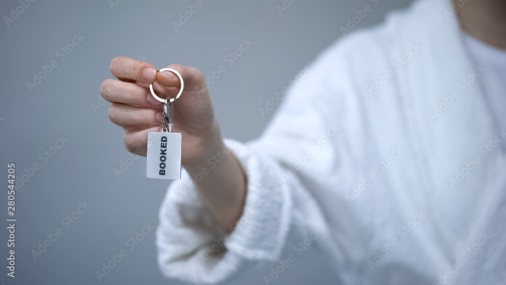 Female client in bathrobe holding keys with Booked word, luxury resort hotel Female client in bathrobe holding keys with Booked word, luxury resort hotel