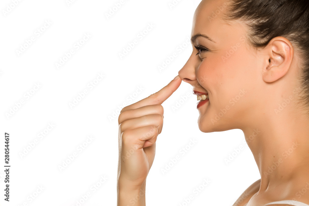 young happy woman touches her nose with her finger on a white background young happy woman touches her nose with her finger on a white background