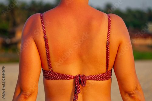Woman applying spf sun cream on tanned shoulder