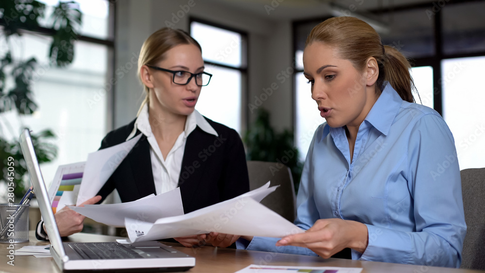 Fototapeta premium Business women quarreling, looking at papers, accusing each other in low income