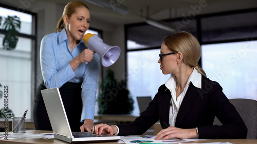 Lady boss shouting with megaphone at colleague, authoritarian leadership photo