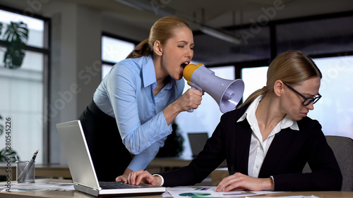 Female boss screaming with megaphone at colleague, authoritarian leadership photo