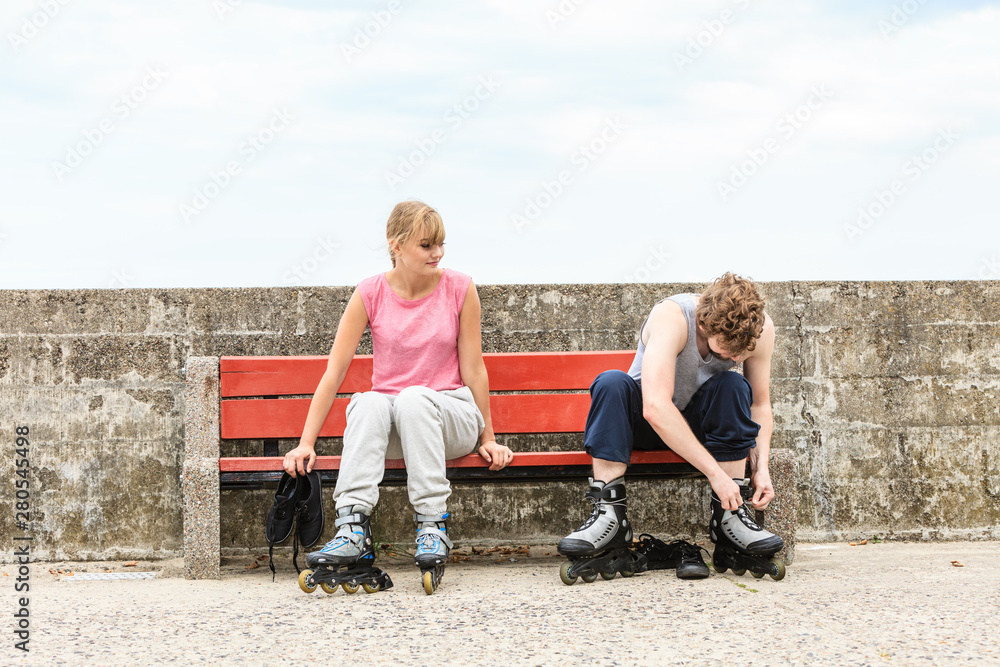 People friends putting on roller skates outdoor.