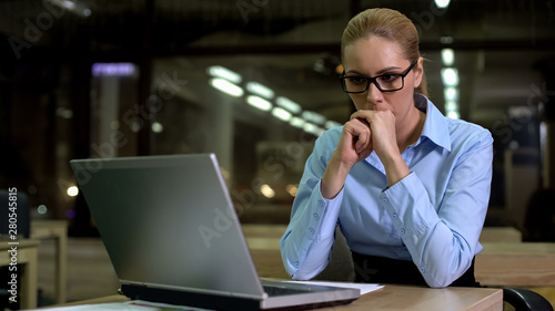 Nervous business woman looking at laptop, afraid of work failure and bad news