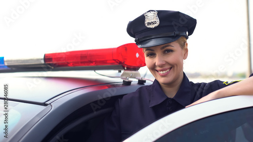 Photo Beautiful lady cop in service cap smiling to camera, woman protecting city