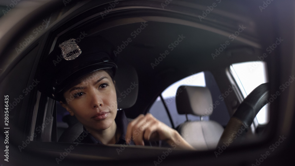 Asian policewoman looking at car mirror, watching risky situation, patrolling