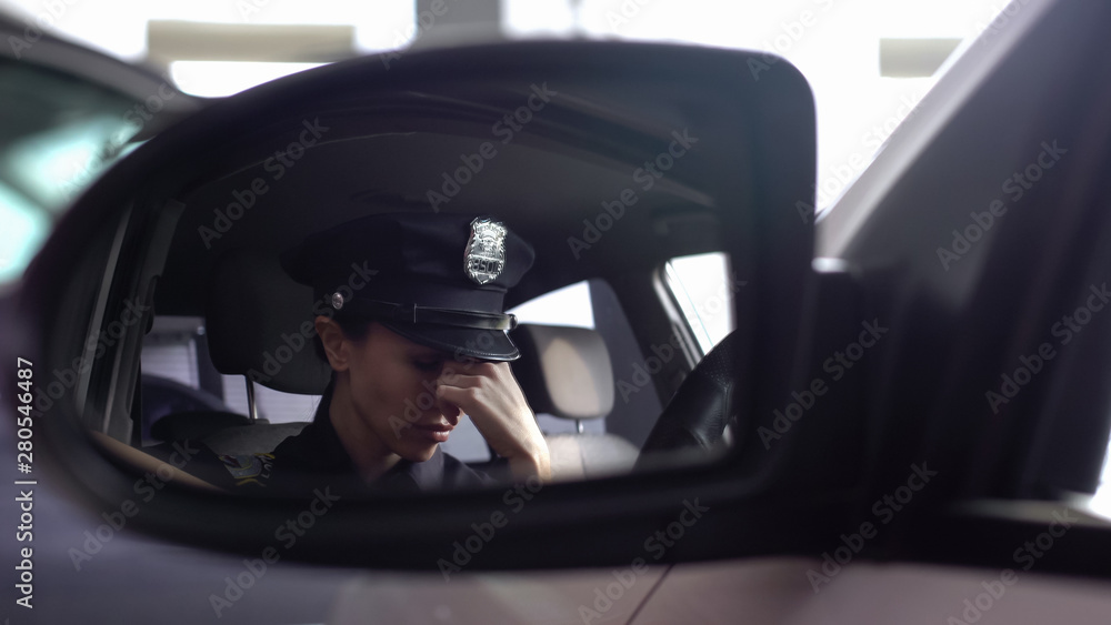 Tired police woman feeling headache, sitting in patrol car, stressed lifestyle