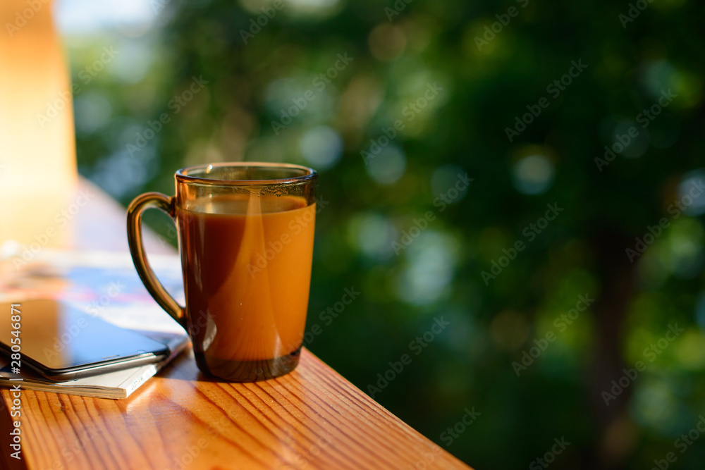 Cup of coffee and cellphone on the windowsill over blurred forest background at sunny summer day. Free copy space. Cup of coffee and cellphone on the windowsill over blurred forest background at sunny summer day. Free copy space.