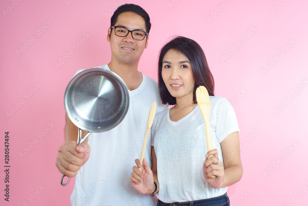 Photos Couple Hold the pan preparing lunch Background pink Photos Couple Hold the pan preparing lunch Background pink