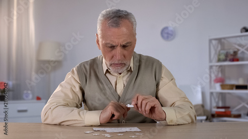 Foto Senior male trying to collect puzzle, memory problems, cognitive impairment