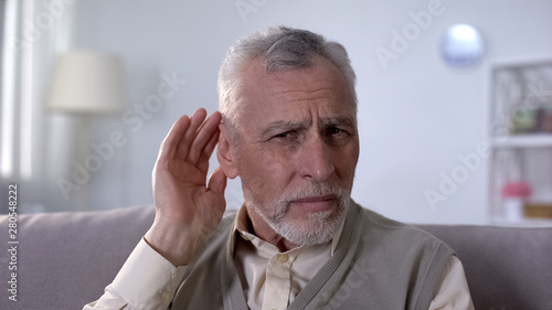 Confused pensioner trying to hear conversation, problem of deafness in old age photo