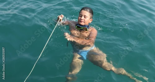 Portrait of a cute teenager boy swimming sea looking at the camera and smiling