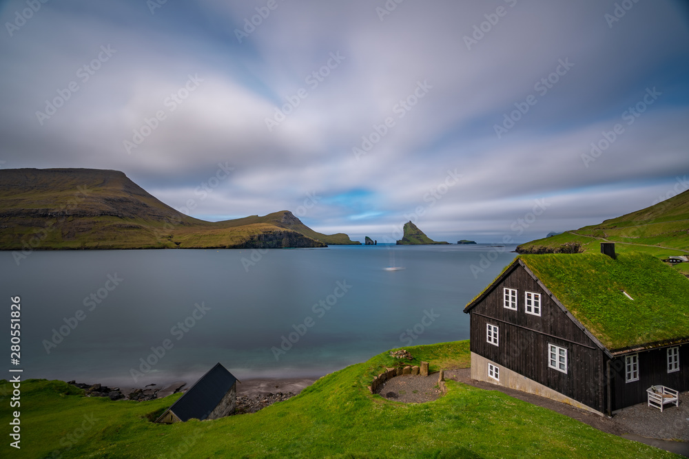 Amazing long exposure of Drangarnir gate, Tindholmur and typical house, Faroe Islands