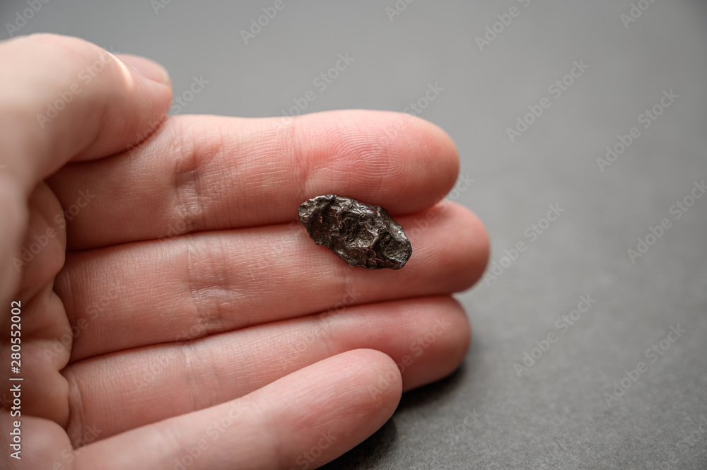 Obraz premium Fragment of the Sikhote-Alin meteorite in hand. Selective focus with shallow depth of field.