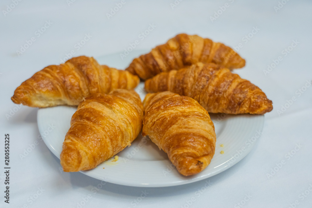 Puffy golden croissants on white plate with white background
