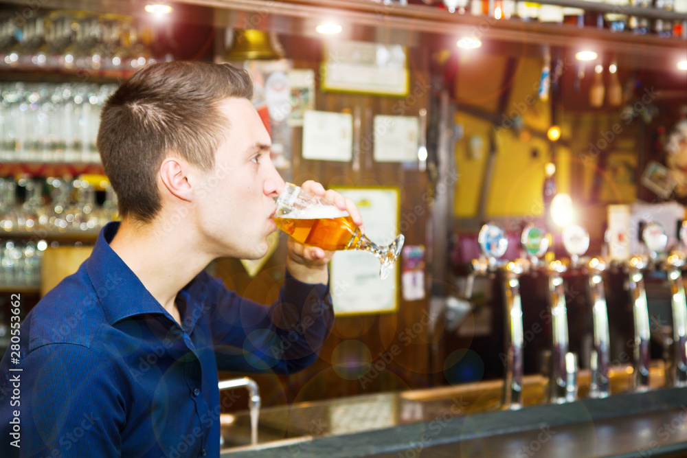 young man drinking beer while sitting in the pub