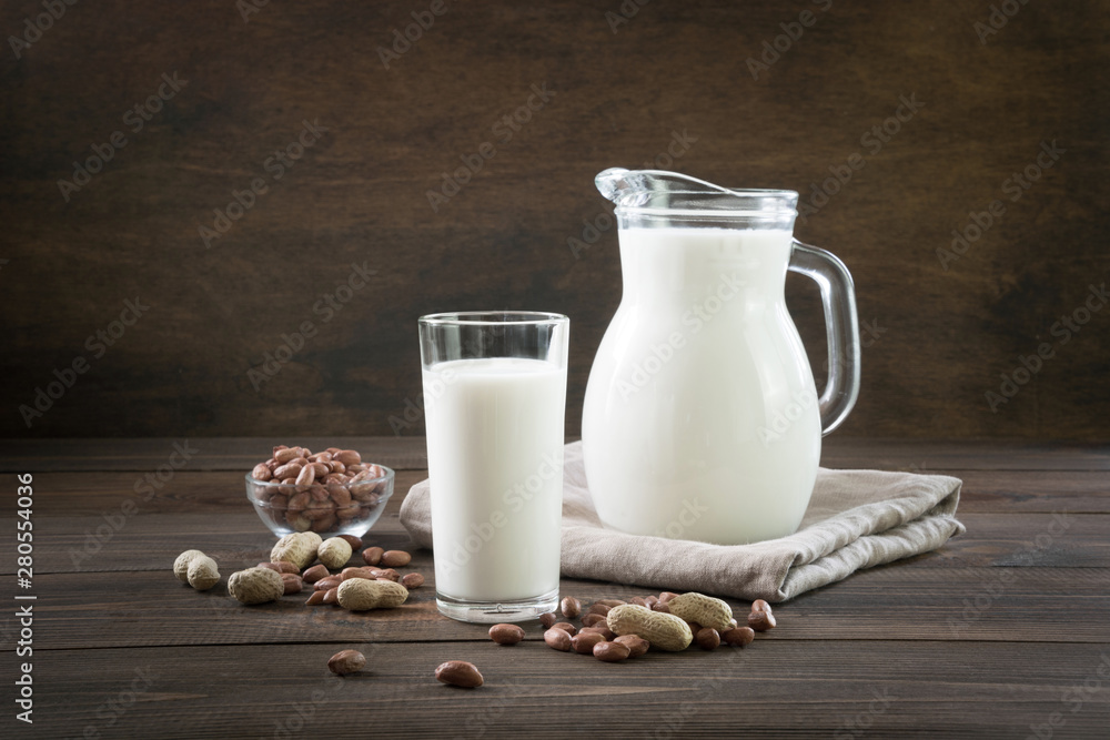 Fresh peanut milk in glass and pitcher on dark wooden table. Rustic style. Fresh peanut milk in glass and pitcher on dark wooden table. Rustic style.