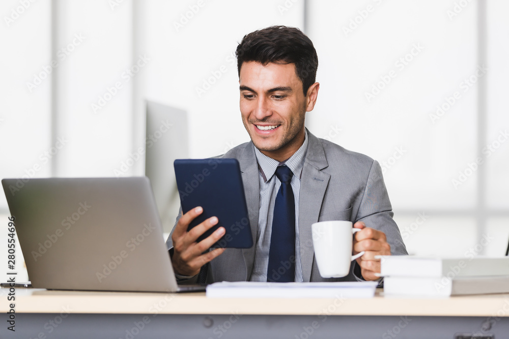Businessman uses tablet computer, drinking coffee.. Businessman uses tablet computer, drinking coffee..