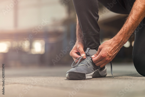 A single man tying his shoelaces, ready to start exercising for an upcoming marathon