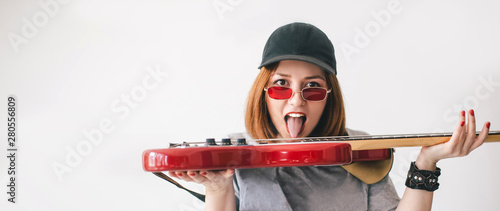 Young beautiful woman musician showing her toungue posing with red bass guitar on white background. Place for text.