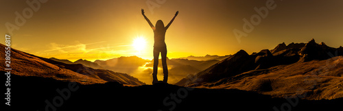 Frau in Siegerpose bei Sonnenaufgang auf einem Berggipfel