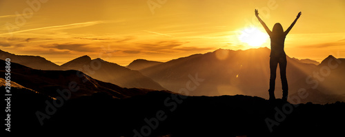 Frau in Siegerpose bei Sonnenaufgang auf einem Berggipfel photo