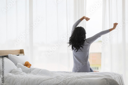 Asian woman stretch lazily in bedroom..