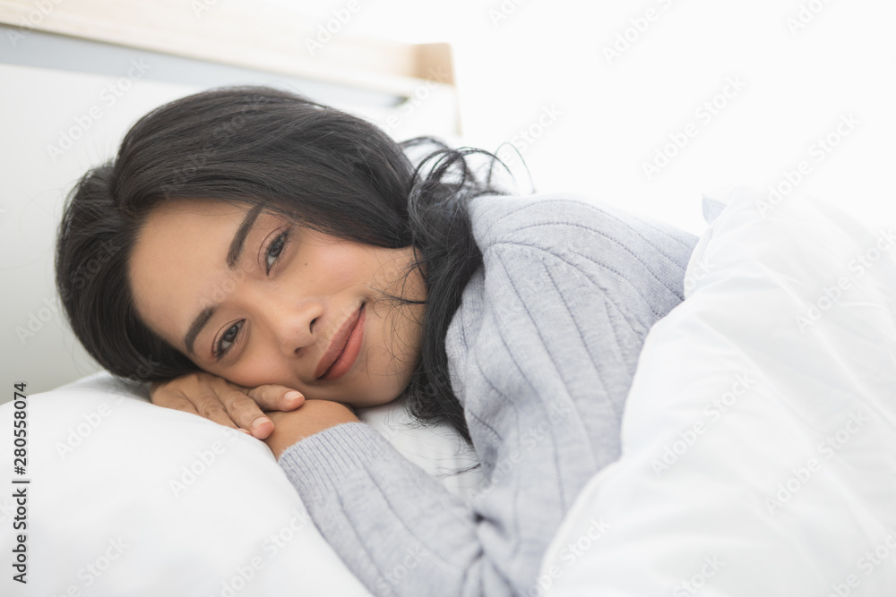 Asian woman lies on one's side on bed in bedroom.. Asian woman lies on one's side on bed in bedroom..