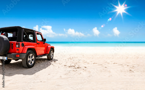 A red jeep on sandy beach and beuatiful blue sunny sky view in summer time. photo