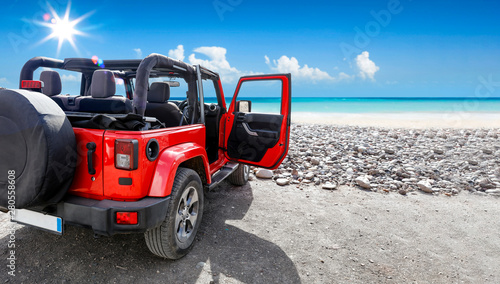A red jeep on sandy beach a...