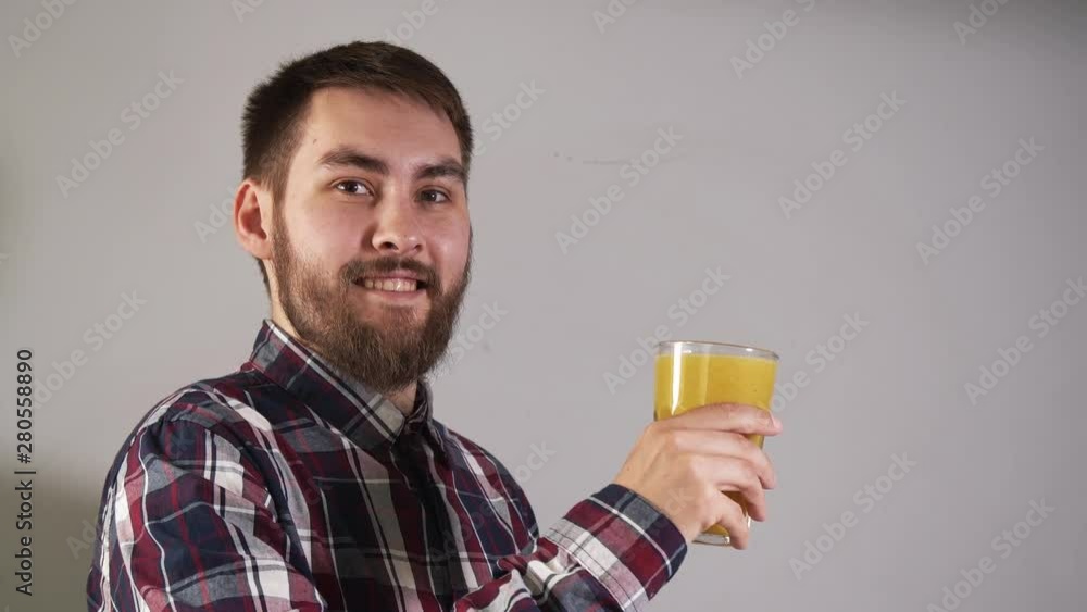 Man raises glass of orange juice closeup and look into the camera with 4K smile Man raises glass of orange juice closeup and look into the camera with 4K smile