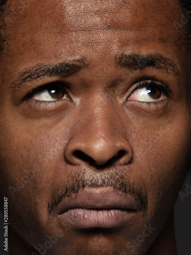 Close up portrait of young and emotional african-american man. Highly detail photoshot of male model with well-kept skin and bright facial expression. Concept of human emotions. Thinking with grimaces